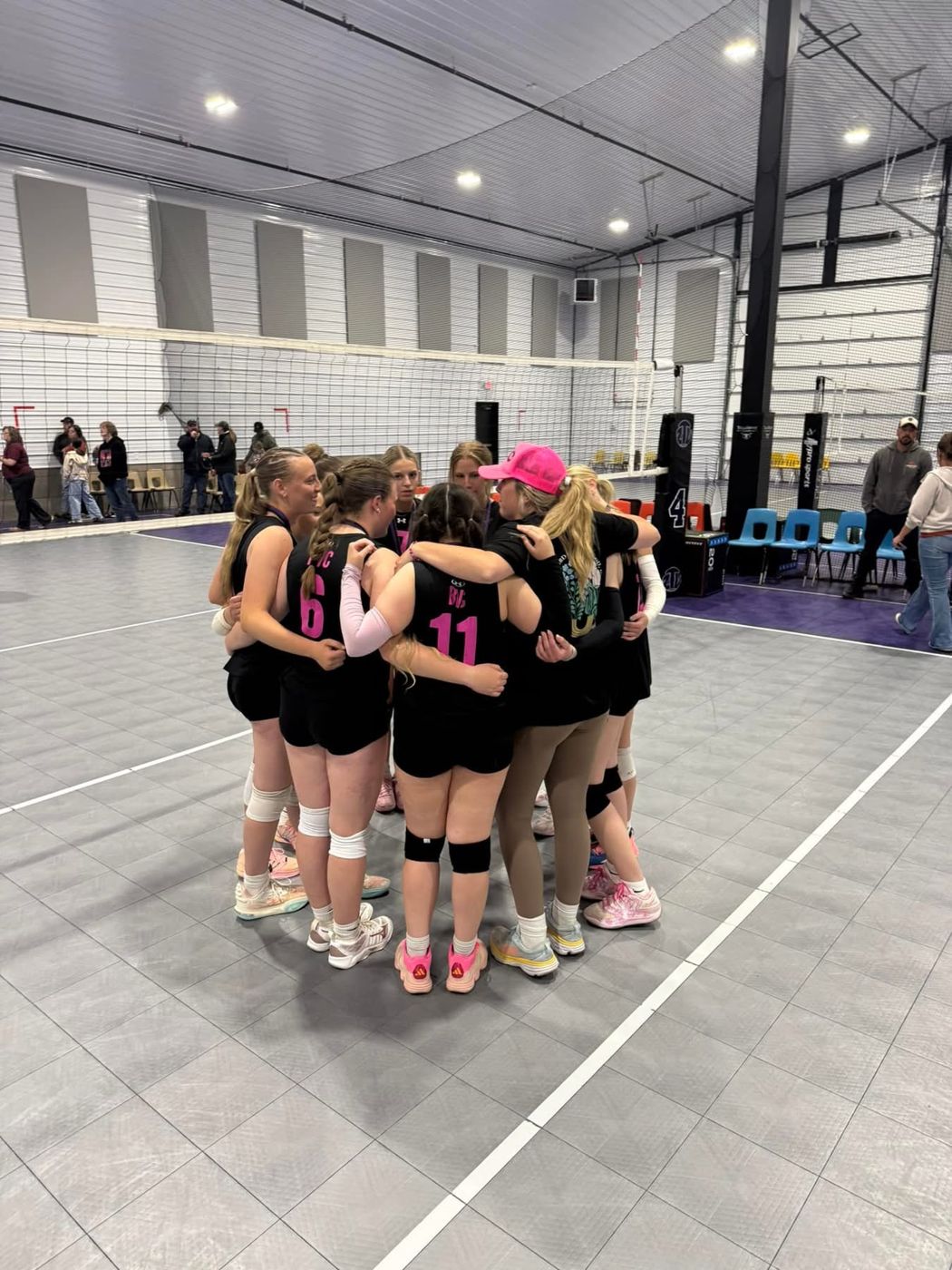 Players in black jerseys in a tight huddle