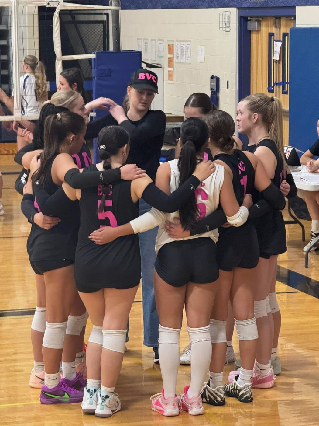 A coach in a BVC hat talking to players during a timeout